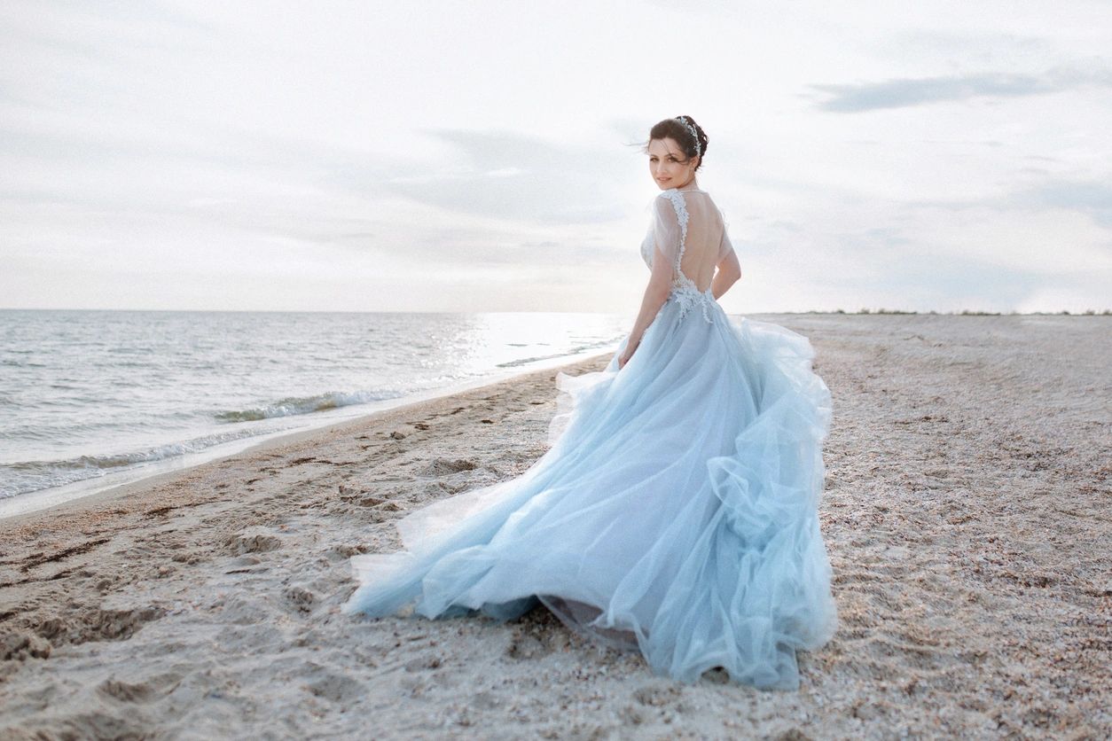 A person wearing a white flowy gown on the beach