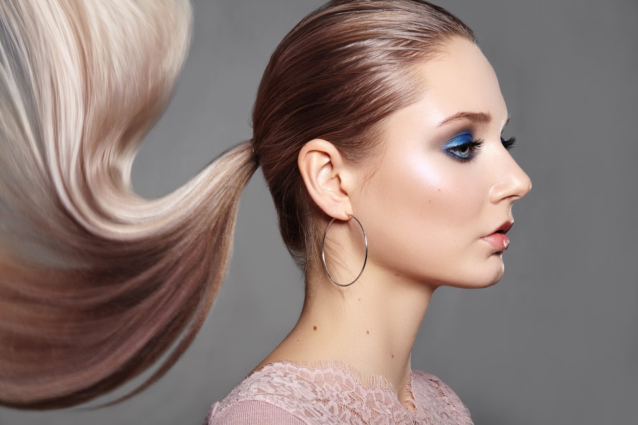 A person with a ponytail hairstyle and blue eyeshadows