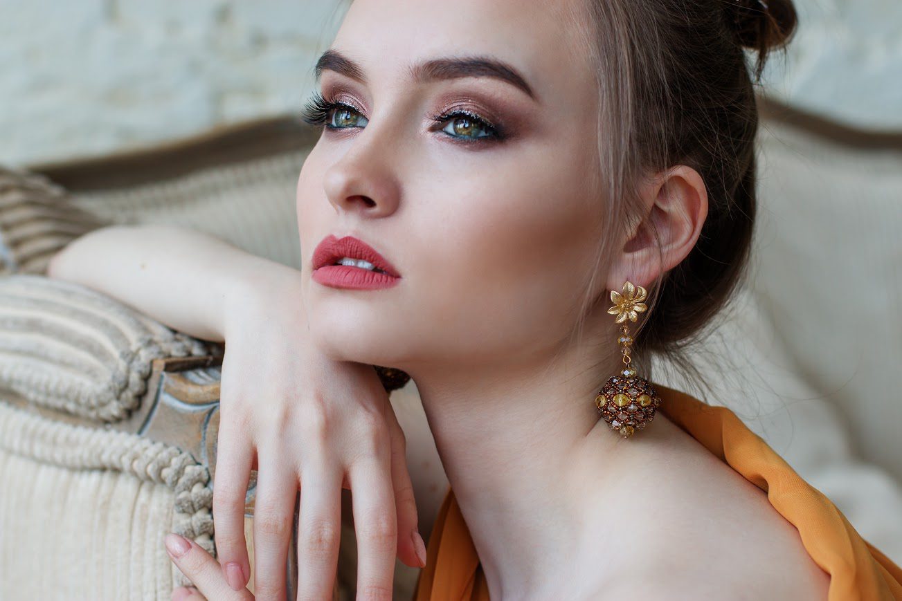 A woman with long hair and green eyes wearing earrings.