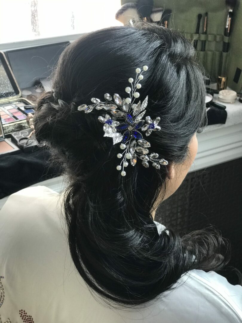 A woman with long black hair wearing a blue and white flower pin.