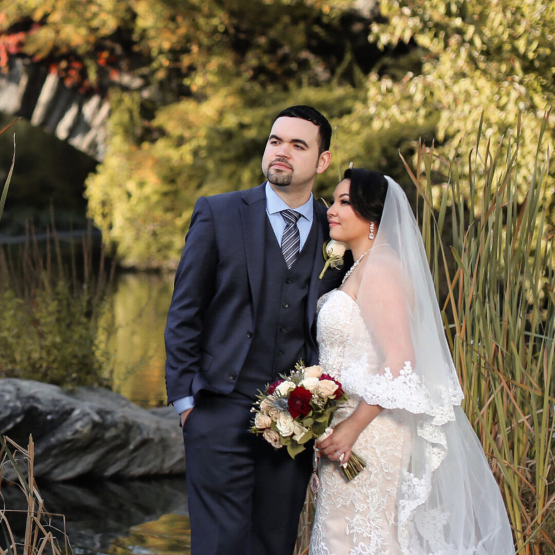A bride and groom standing near the lake