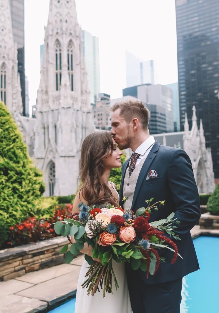 A man and woman kissing in front of a city.